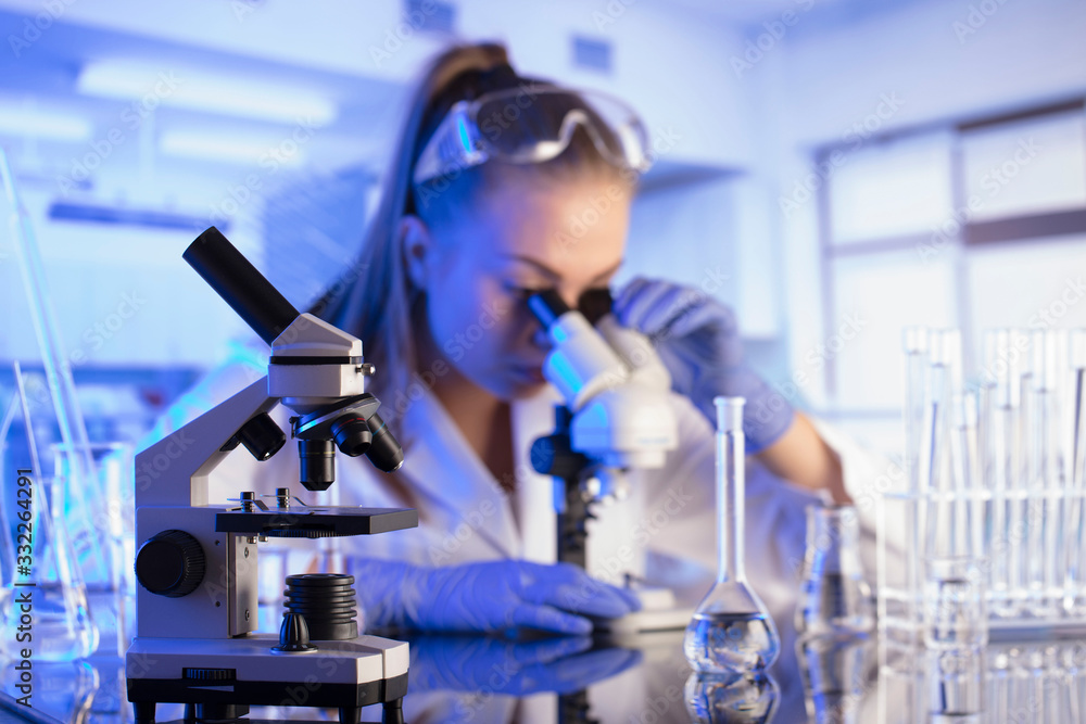 Laboratory interior. Science research concept. Young scientist during experiment and using microscope in modern laboratory. Laboratory interior. Science research concept. Young scientist during experiment and using microscope in modern laboratory.