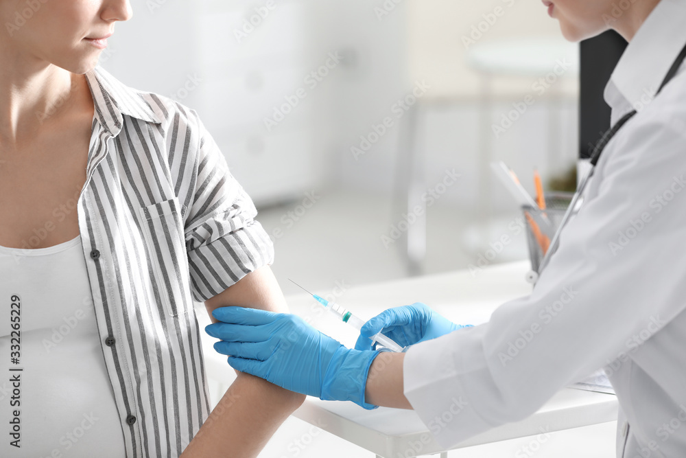 Fototapeta premium Doctor giving injection to pregnant woman in hospital, closeup. Vaccination concept