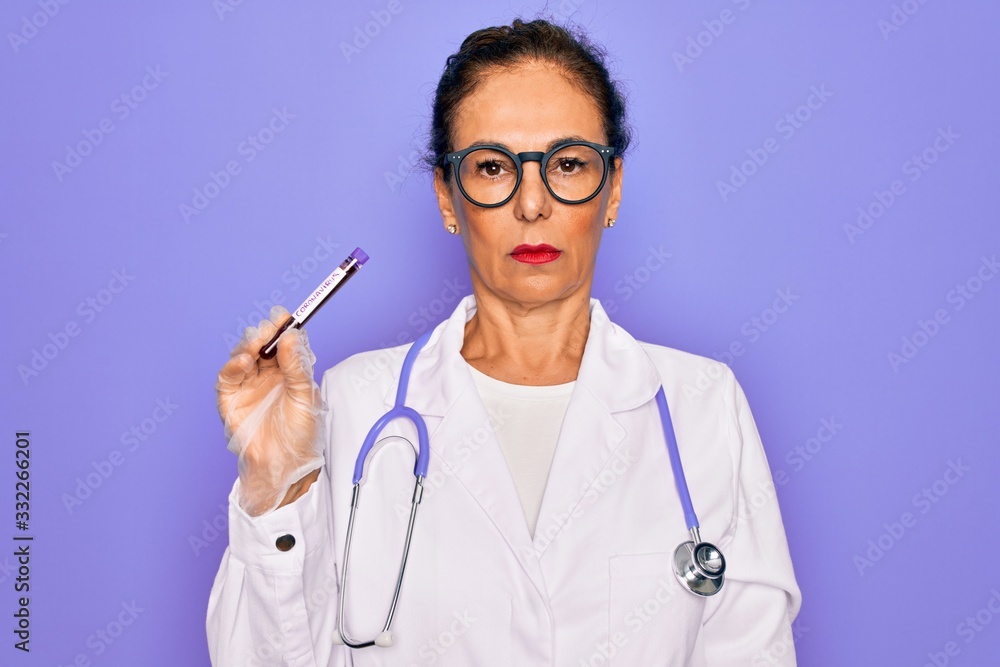 Middle age senior female doctor holding medice blood sample of coronavirus infection disease with a confident expression on smart face thinking serious Middle age senior female doctor holding medice blood sample of coronavirus infection disease with a confident expression on smart face thinking serious