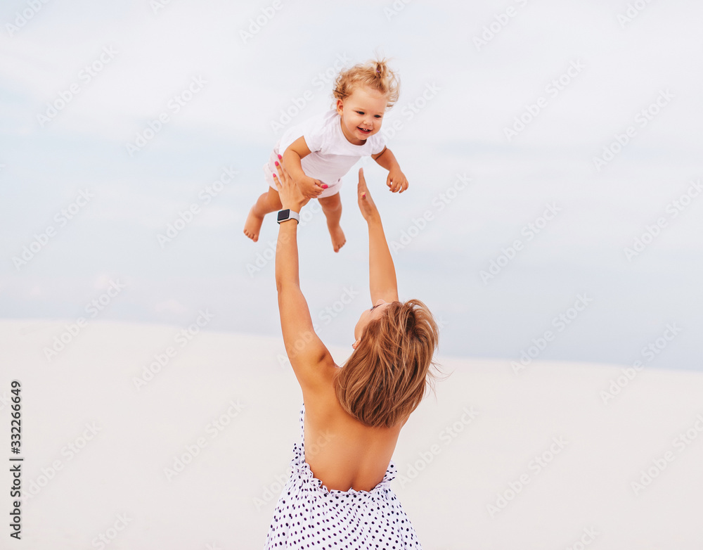 Young mother throwing baby girl in the air at the beach Stock Photo