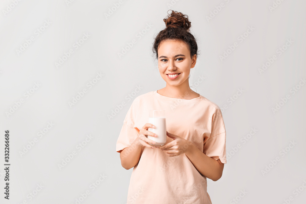 Young pregnant African-American woman with milk on light background Young pregnant African-American woman with milk on light background