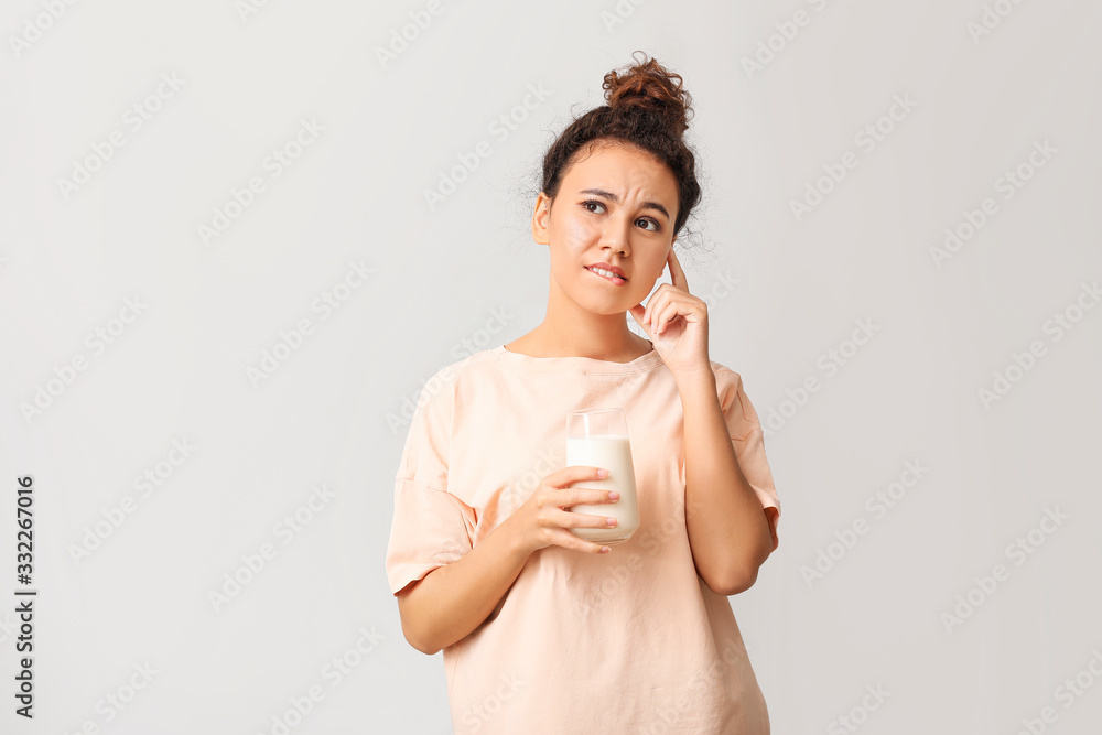 Young pregnant African-American woman with milk on light background Young pregnant African-American woman with milk on light background
