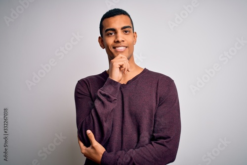 Young handsome african american man wearing casual sweater over white background looking confident at the camera with smile with crossed arms and hand raised on chin. Thinking positive.