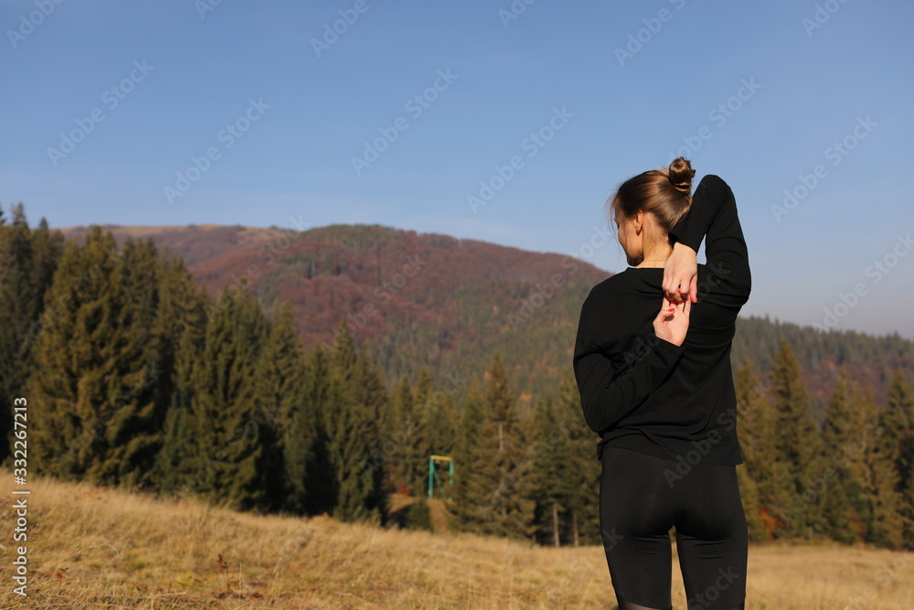 Young woman doing stretching exercises on nature in mountains. Sports girl practicing yoga pose in leggings. beautiful forest landscape Young woman doing stretching exercises on nature in mountains. Sports girl practicing yoga pose in leggings. beautiful forest landscape