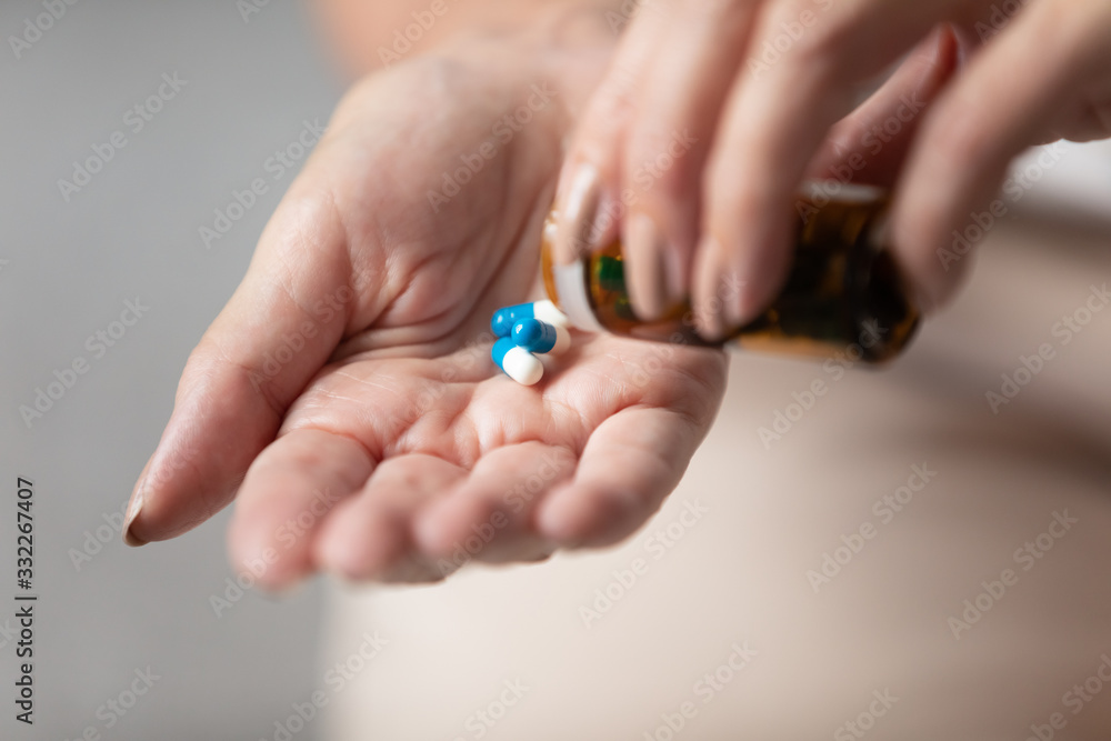 Close up older wrinkled female hands taking medicament pills out of bottle. Middle aged woman preparing take nutrition supplements, vitamins, antibiotics, emergency medicine. Healthcare concept. Close up older wrinkled female hands taking medicament pills out of bottle. Middle aged woman preparing take nutrition supplements, vitamins, antibiotics, emergency medicine. Healthcare concept.