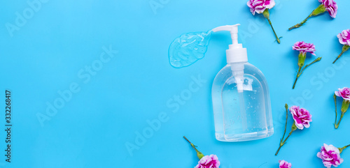 Fototapeta Naklejka Na Ścianę i Meble -  Alcohol hand sanitizer gel in pump bottle with carnation flower on blue background.
