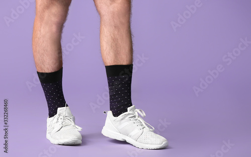 Male legs in socks and shoes on color background