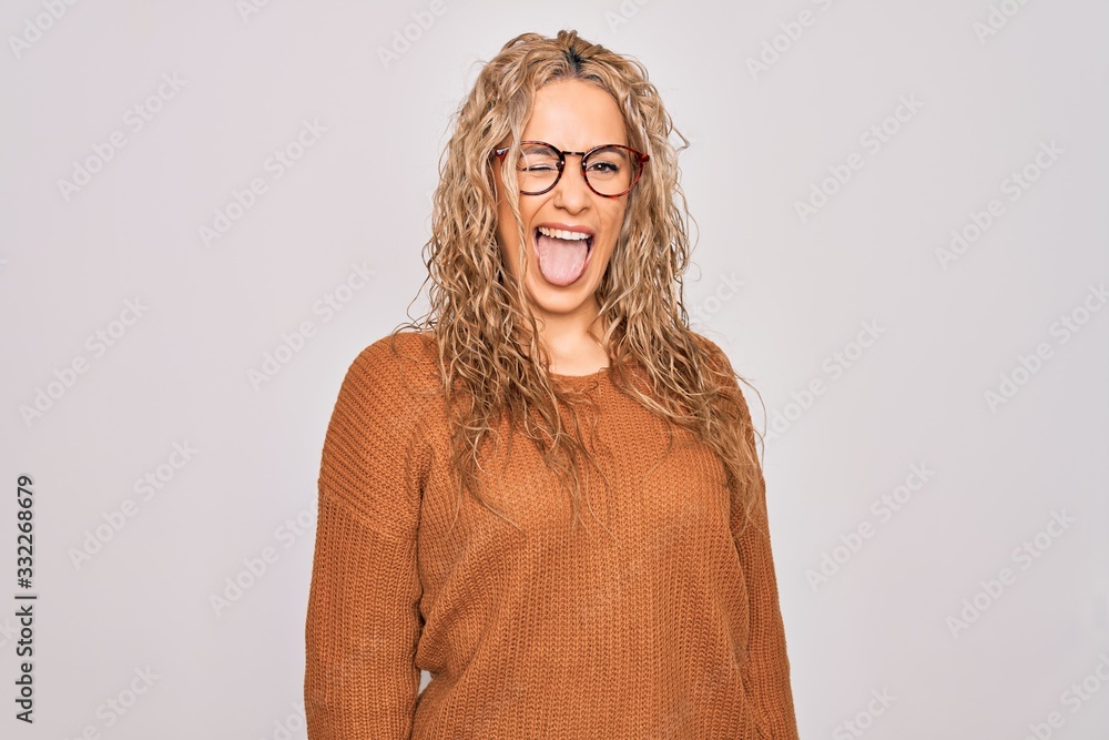 Young beautiful blonde woman wearing casual sweater and glasses over white background winking looking at the camera with sexy expression, cheerful and happy face. Young beautiful blonde woman wearing casual sweater and glasses over white background winking looking at the camera with sexy expression, cheerful and happy face.