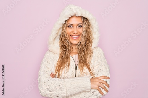 Young beautiful blonde woman wearing casual sweater with hood over isolated pink background happy face smiling with crossed arms looking at the camera. Positive person.