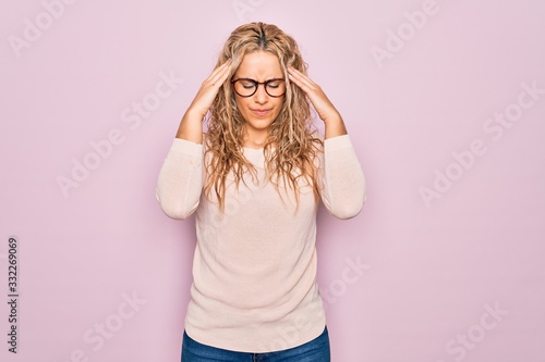 Young beautiful blonde woman wearing casual sweater and glasses over pink background with hand on head for pain in head because stress. Suffering migraine.