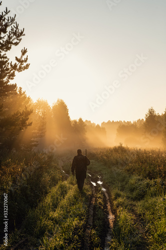 Silhouetted of a hunter with shotgun at beautiful sunset