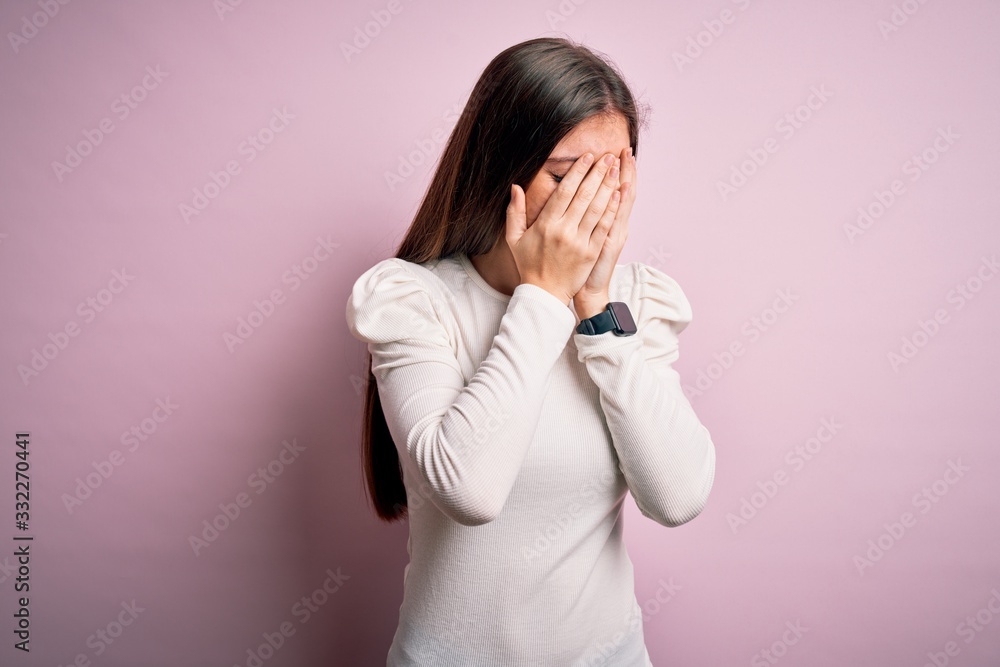 Young beautiful woman with blue eyes wearing casual white t-shirt over pink background with sad expression covering face with hands while crying. Depression concept. Young beautiful woman with blue eyes wearing casual white t-shirt over pink background with sad expression covering face with hands while crying. Depression concept.