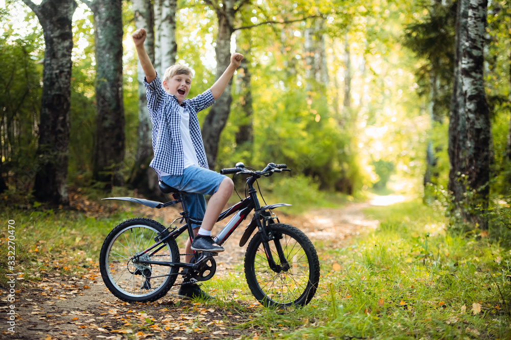Fototapeta premium Joyful boy on a bicycle with his parents in the park