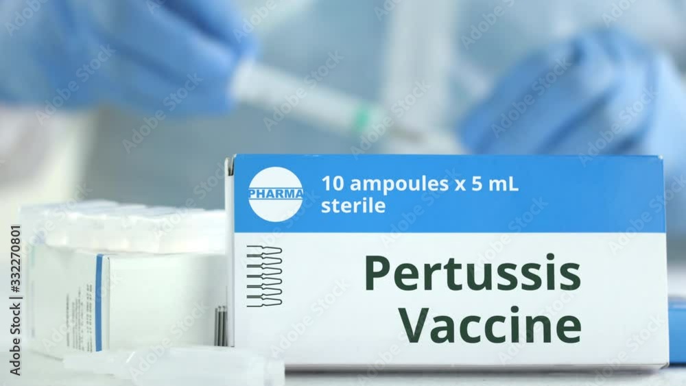 Box with pertussis vaccine on the table against blurred lab assistant or doctor. Fictional phaceutical logo Box with pertussis vaccine on the table against blurred lab assistant or doctor. Fictional phaceutical logo