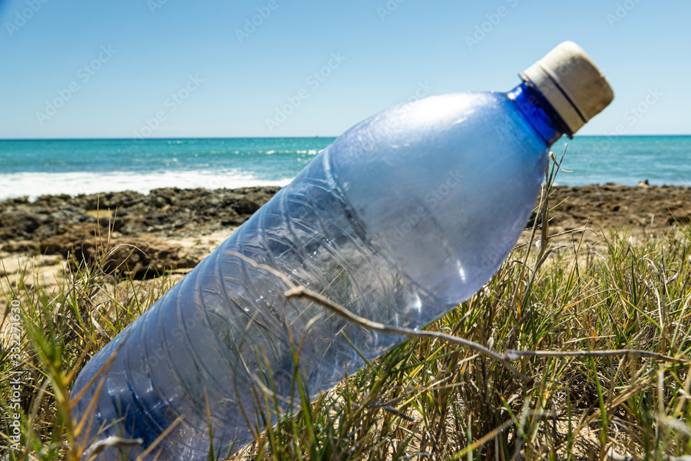Plastic water bottle on the beach in Hawaii with tropical surroundings and beautiful aqua water in the ocean behind them. Plastic water bottle on the beach in Hawaii with tropical surroundings and beautiful aqua water in the ocean behind them.