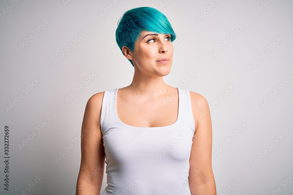Young beautiful woman with blue fashion hair wearing casual t-shirt over white background smiling looking to the side and staring away thinking. Young beautiful woman with blue fashion hair wearing casual t-shirt over white background smiling looking to the side and staring away thinking.