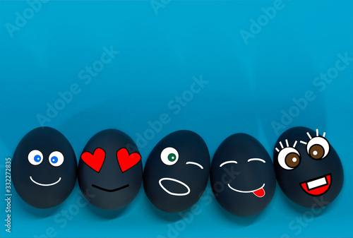 Easter eggs 5 pieces with the image of emojis, funny faces drawn isolated, on a blue background, flat lay. Easter and spring holiday concept. Copy space, top view. photo