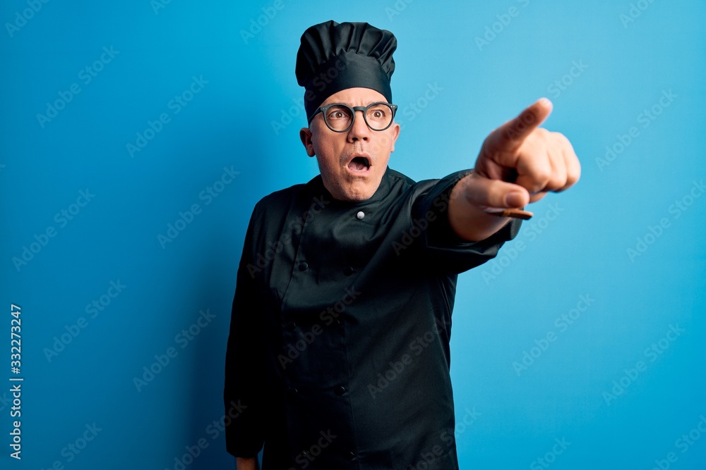 Middle age handsome grey-haired chef man wearing cooker uniform and hat Pointing with finger surprised ahead, open mouth amazed expression, something on the front Middle age handsome grey-haired chef man wearing cooker uniform and hat Pointing with finger surprised ahead, open mouth amazed expression, something on the front
