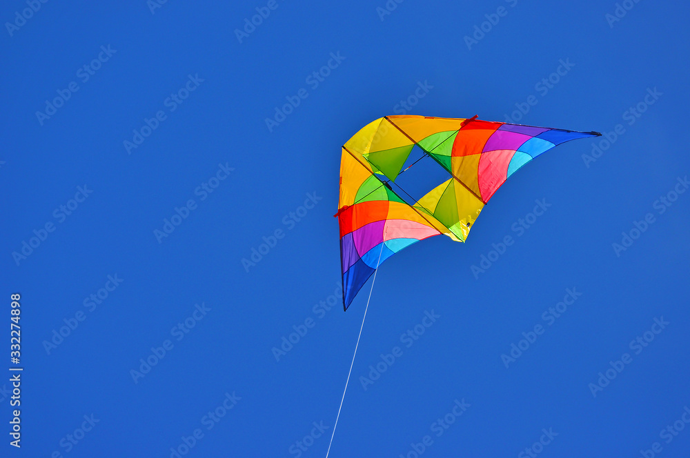 A colorful kite flying in the blue sky A colorful kite flying in the blue sky