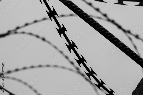 Monochrome photo of detail of barbed wire. Steel border. Prison, military or quarantine concept photo