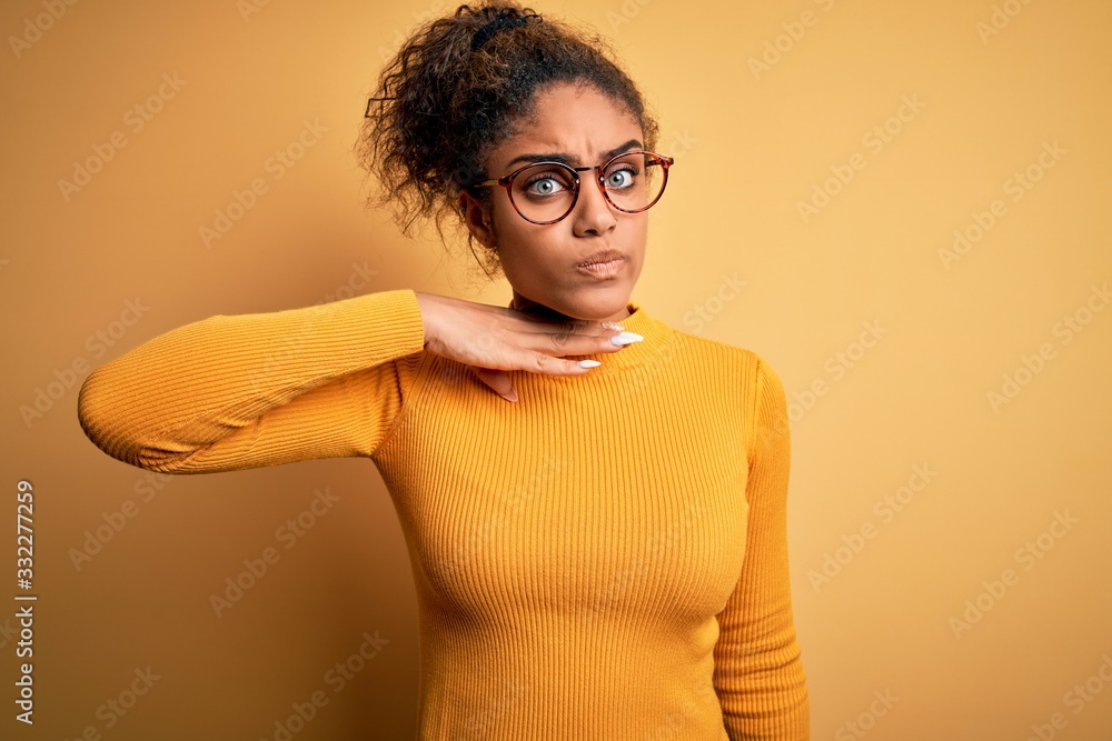 Young beautiful african american girl wearing sweater and glasses over yellow background cutting throat with hand as knife, threaten aggression with furious violence Young beautiful african american girl wearing sweater and glasses over yellow background cutting throat with hand as knife, threaten aggression with furious violence