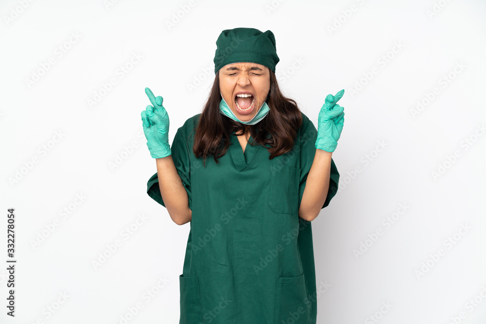 Surgeon woman in green uniform isolated on white background with fingers crossing Surgeon woman in green uniform isolated on white background with fingers crossing