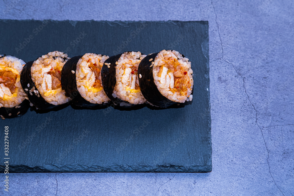 Kimchi kimbap with omelette on a slate place on concrete background. Korean cuisine. Kimchi kimbap with omelette on a slate place on concrete background. Korean cuisine.