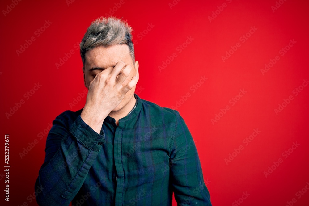 Young handsome modern man wearing elegant green shirt over red isolated background tired rubbing nose and eyes feeling fatigue and headache. Stress and frustration concept. Young handsome modern man wearing elegant green shirt over red isolated background tired rubbing nose and eyes feeling fatigue and headache. Stress and frustration concept.
