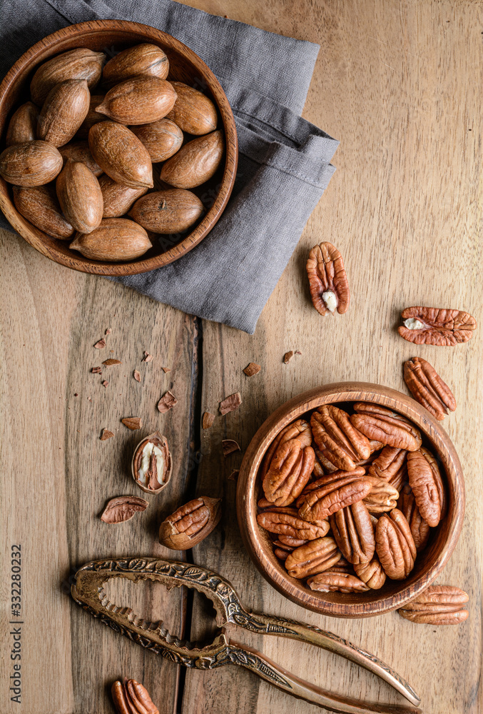 Healthy snack rich in vitamins and minerals, fresh shelled and in-shell pecans in a bowl Healthy snack rich in vitamins and minerals, fresh shelled and in-shell pecans in a bowl