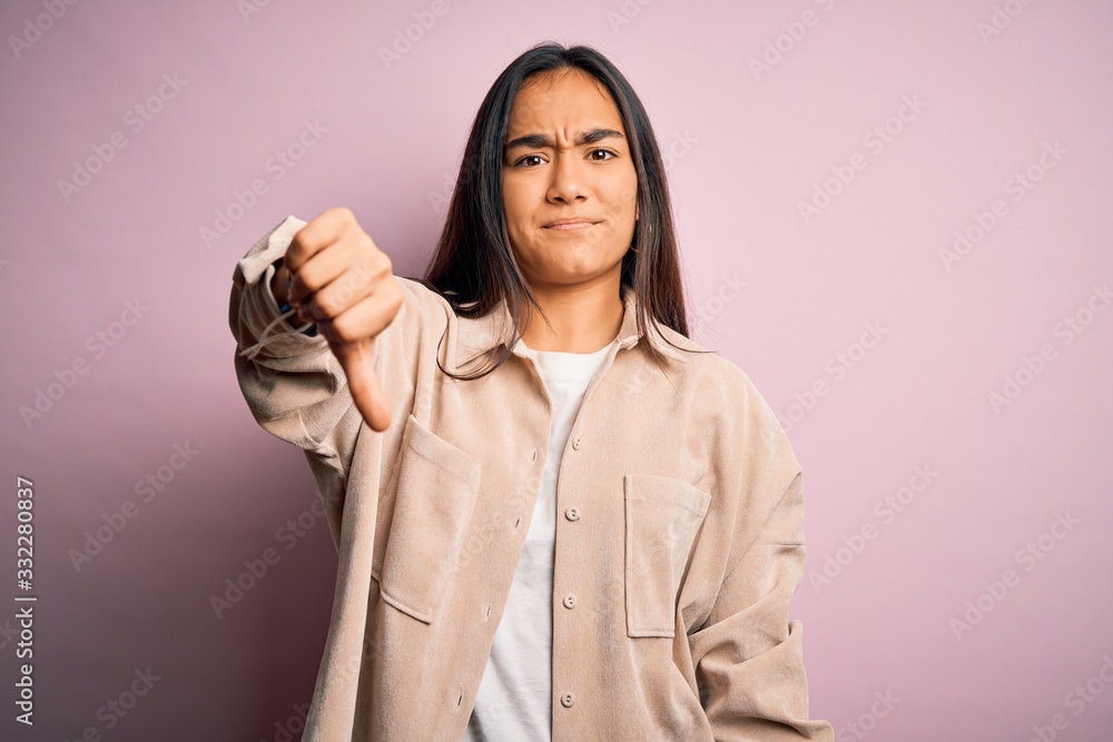 Young beautiful asian woman wearing casual shirt standing over pink background looking unhappy and angry showing rejection and negative with thumbs down gesture. Bad expression. Young beautiful asian woman wearing casual shirt standing over pink background looking unhappy and angry showing rejection and negative with thumbs down gesture. Bad expression.