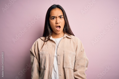 Young beautiful asian woman wearing casual shirt standing over pink background In shock face, looking skeptical and sarcastic, surprised with open mouth © Krakenimages.com