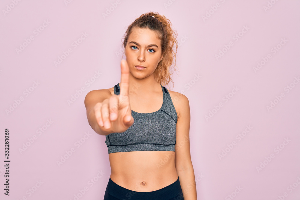 Young beautiful blonde sportswoman with blue eyes doing exercise wearing sportswear Pointing with finger up and angry expression, showing no gesture