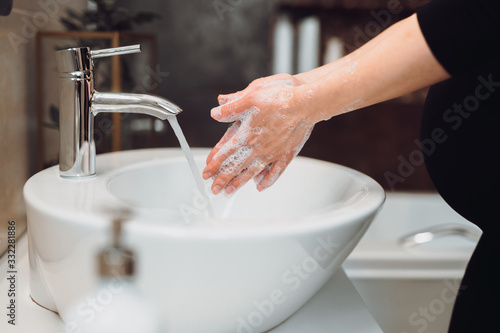 pregnant woman Washing hands with soap under the faucet with water at home in bathroom.