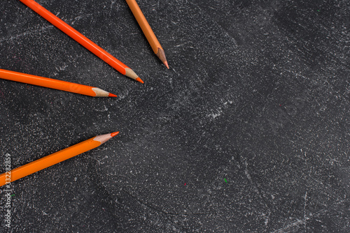 Orange pencils on a black stone table © Evgeny