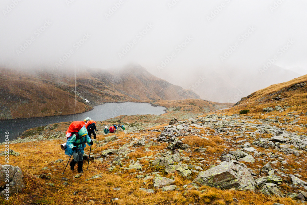 Tourists travelers with backpacks climb the rocks in dense fog. Poor visibility and easy to get lost. Caucasus Mountains, Arkhyz