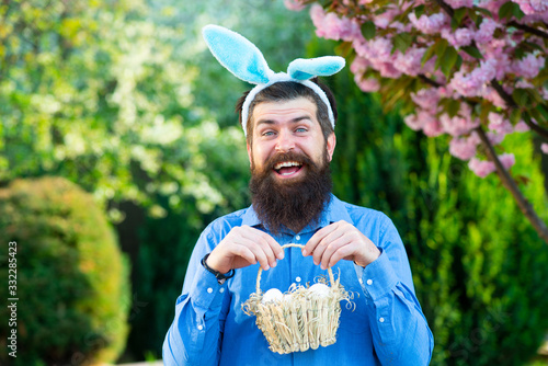 Funny man hunting easter eggs. Portrait of Easter man holds basket with Easter egg. Spring holidays. photo