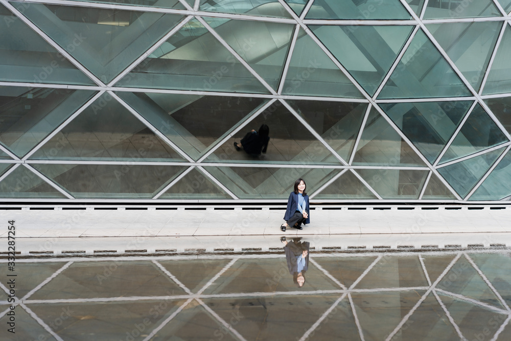 Young business women passing through glass buildings Young business women passing through glass buildings