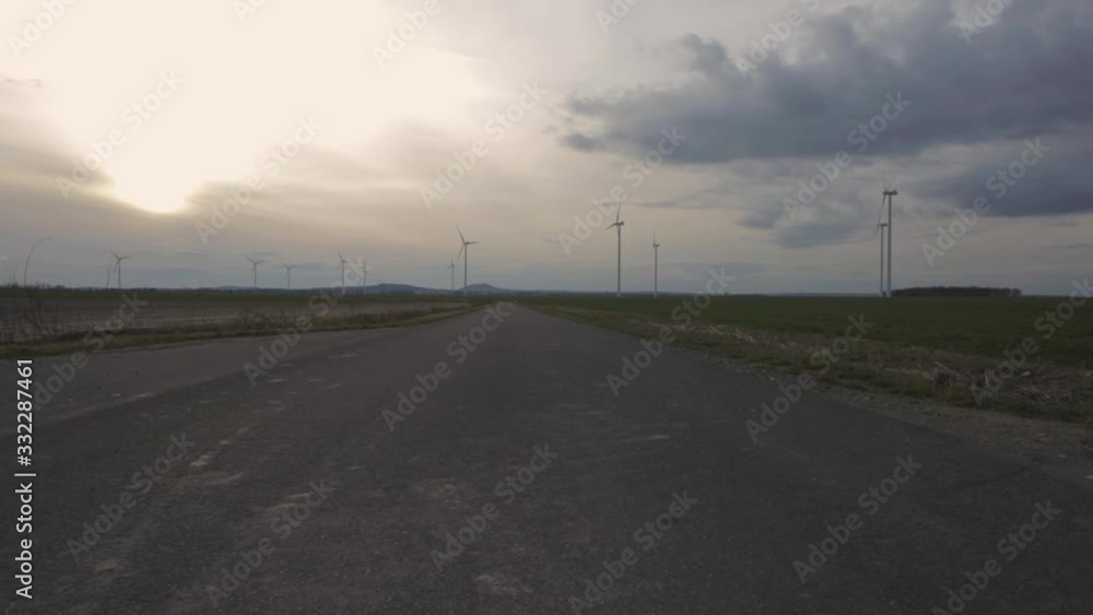 A long concrete road heading to the farm windmills in the countryside - Pan tilt shot A long concrete road heading to the farm windmills in the countryside - Pan tilt shot