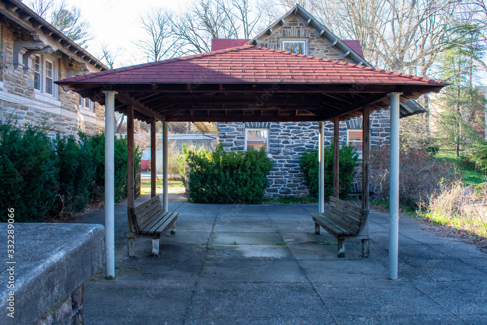 A Red Gazebo in a Court Yard With Two Benches Underneath