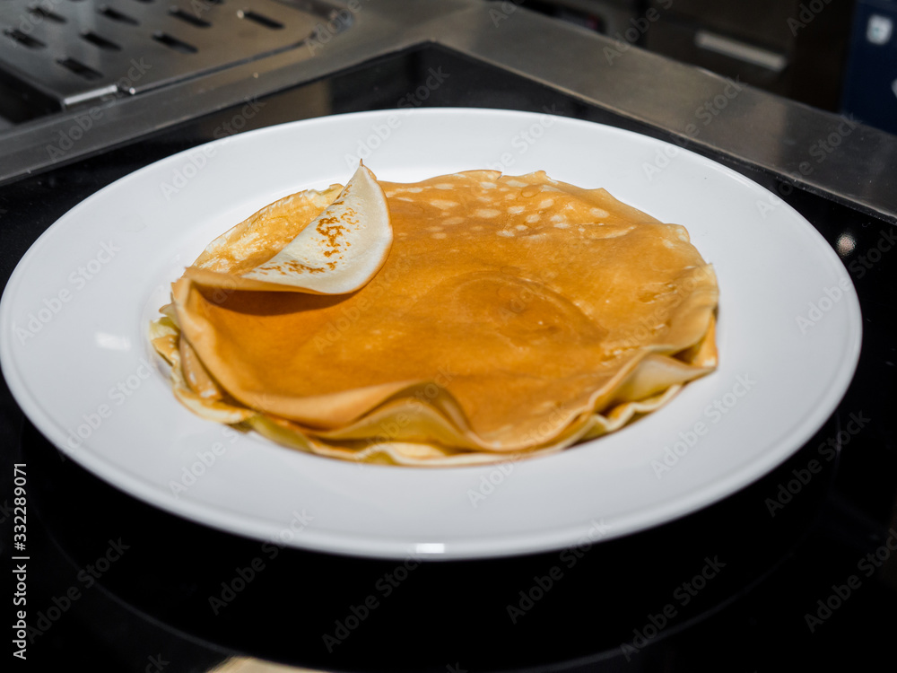 Hot fresh pancakes on a white plate in the kitchen Hot fresh pancakes on a white plate in the kitchen
