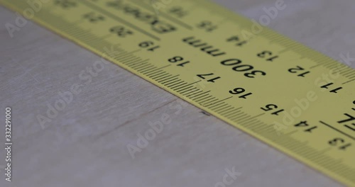 Drawing a straight line with ruler and pencil on a wooden surface