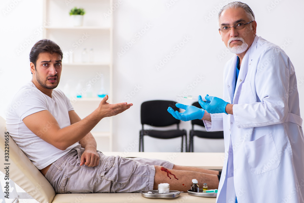Obraz premium Leg injured man visiting old doctor in first aid concept