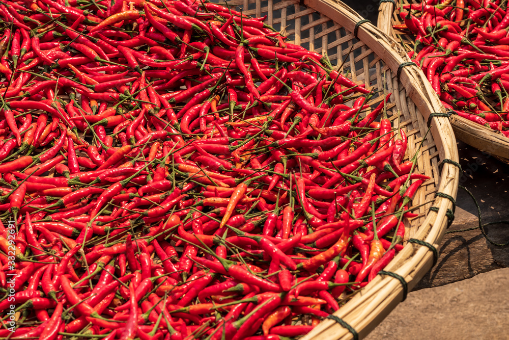 Fototapeta premium Many red chillies lay in a basket during the day time in the sun.