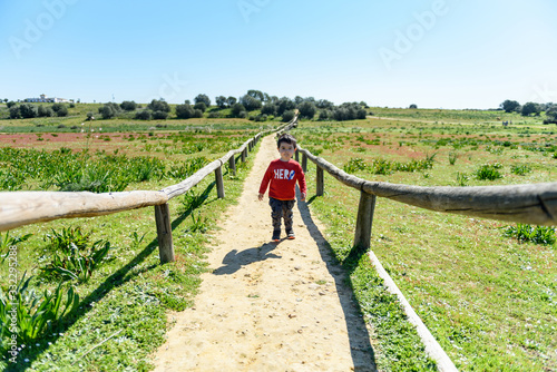 Niño pequeño con camiseta roja en prado verde 