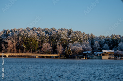 Snow covered trees on a clear sunny morning at the boathouse at Lake Johnson Park in Raleigh, North Carolina. © Samuel