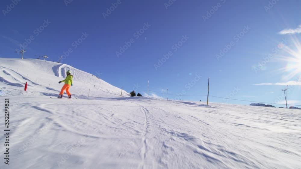 girl snowboarding on slopes in the Swiss alps, sun rays and flare visible in the background girl snowboarding on slopes in the Swiss alps, sun rays and flare visible in the background