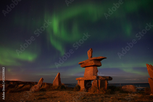 northern lights in churchill manitoba with an iconic inukshuk in the foreground