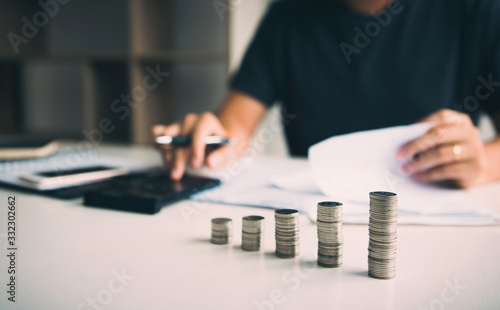 Asian men are calculating about finances about the cost or future investment at home while the coins are arranged with the idea of saving. photo