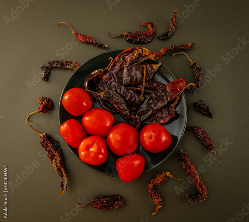 Still life photograph with tomatoes, Pasilla peppers and dried chilacas, on a table with green tablecloth, ingredients used in traditional Mexican cuisine photo