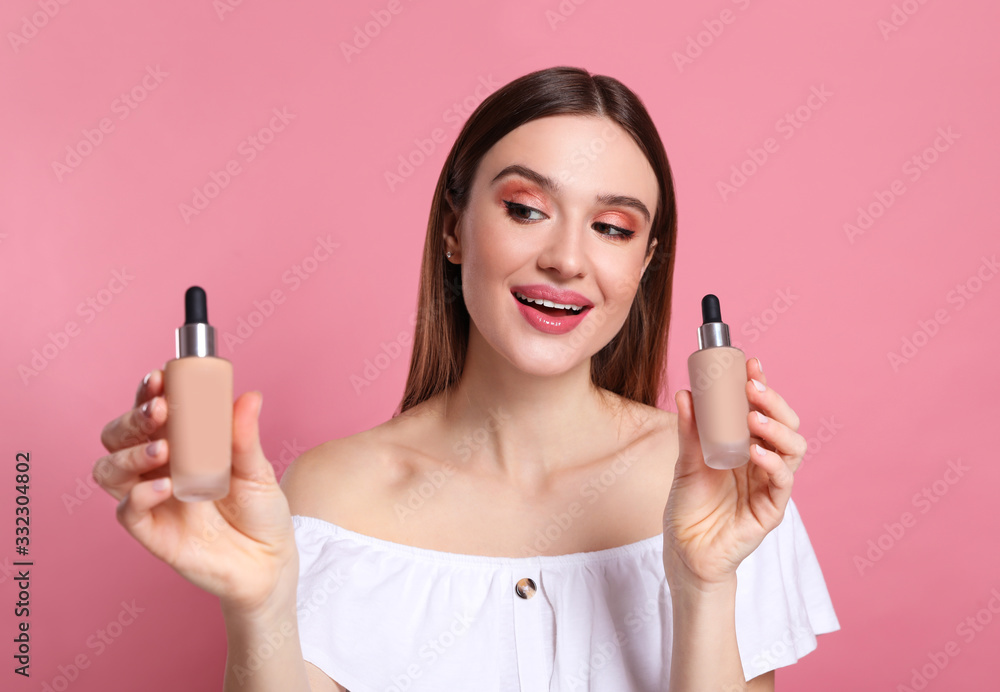 Beauty blogger showing bottles of foundation on pink background Beauty blogger showing bottles of foundation on pink background